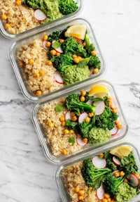 four glass containers filled with rice, broccoli and lemons