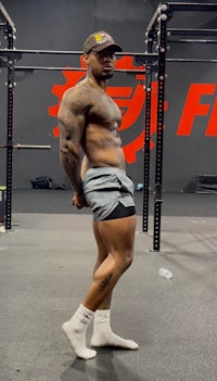 a man posing in front of a barbell in a gym