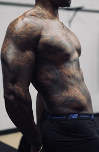 a man with tattoos posing in a gym